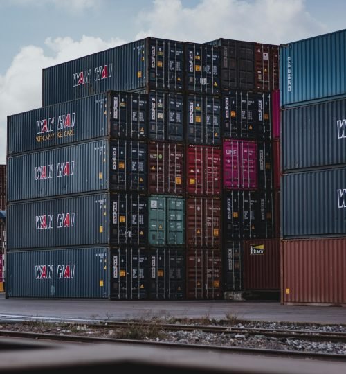 High vertical stack of cargo containers at a port, symbolizing global logistics.